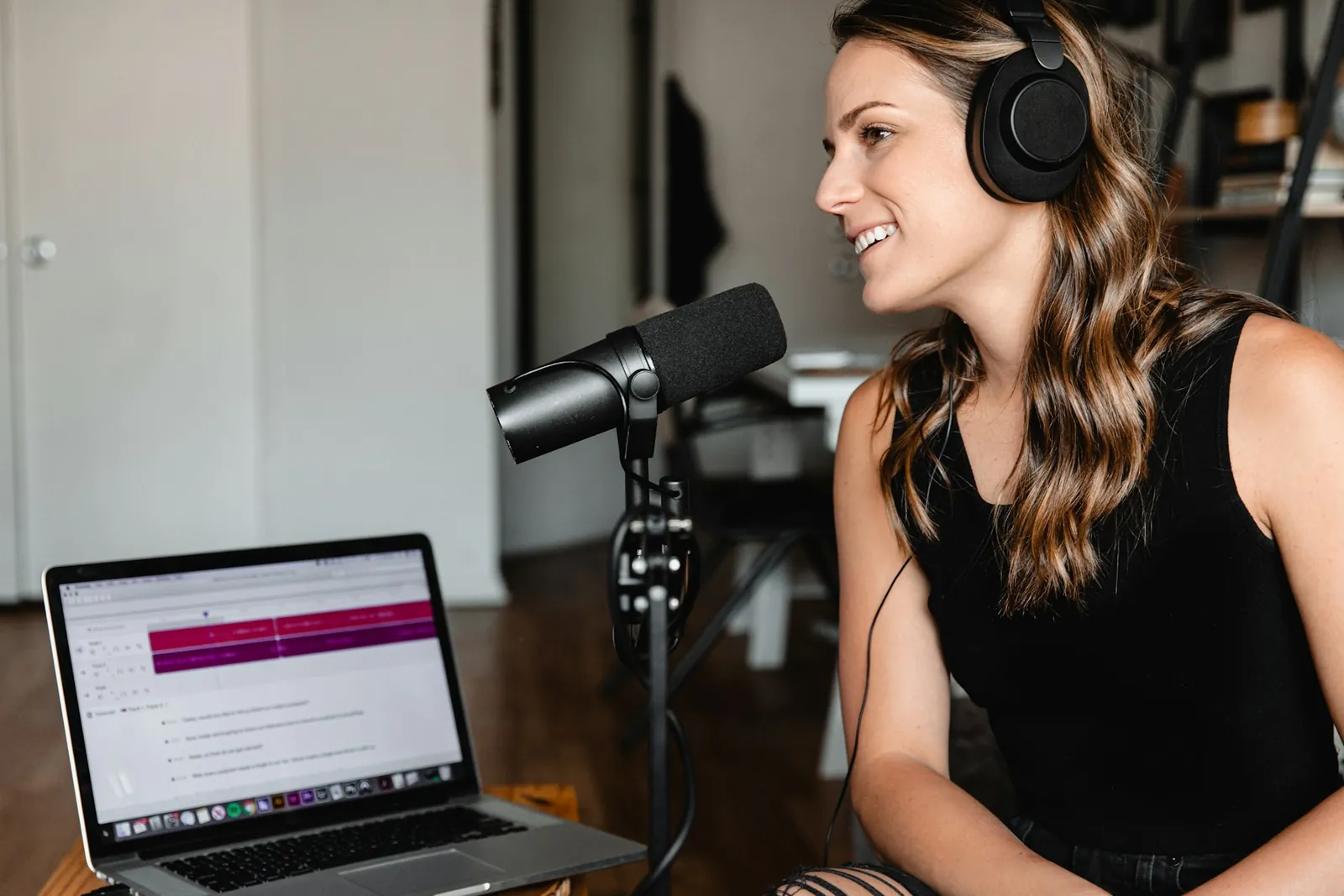 A narrator wearing headphones recording at a studio microphone